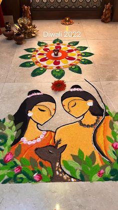 two women are sitting on the floor in front of a flower arrangement with candles and flowers