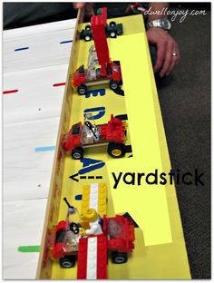 a close up of a toy train set on a table with yellow background and words that read yard stick