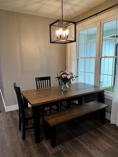 a dining room table and bench in front of a large window with flowers on it