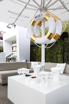 a white table topped with lots of glasses under a gold and white umbrella over it