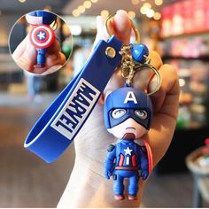 the captain keychain is being held up by someone's hand and has an iron man figure on it