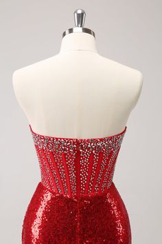 the back of a red dress with silver sequins on it and a white mannequin