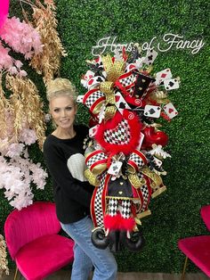 a woman holding a large red and black christmas wreath in front of a green wall