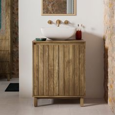 a bathroom with a sink and mirror on the wall next to a wooden cabinet in front of a brick wall