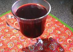 a glass cup filled with liquid sitting on top of a colorful table cloth covered place mat