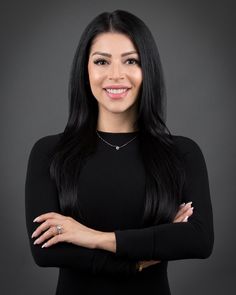 a woman with long black hair and wearing a black dress is smiling at the camera