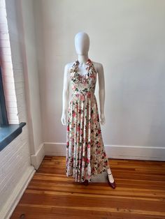 This is such a lovely 70s tiered ruffle maxi dress! The dress is cream with a lovely pattern made up of pink, yellow and blue flowers and bouquets. This dress has a unique ruffle halter neck tie that is adjustable and zipper in the back. It is made of a soft and smooth acetate that is thick enough to not be see through when the light hits, even though it is unlined. The perfect dress to throw on in the Summer or Spring. This dress is just so pretty! Imagine all the complements and conversations Fitted Beige Maxi Dress With Ruffles, Cream Tiered Flowy Maxi Dress, Flowy Tiered Cream Maxi Dress, Cream Floral Print Maxi Dress, Fitted Beige Vintage Maxi Dress, Fitted Beige Maxi Length Vintage Dress, Vintage Flowy Maxi Dress For Garden Party, Vintage Flowy Floor-length Maxi Dress, Cream Tiered Fitted Maxi Dress