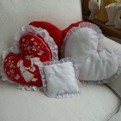 three red and white heart shaped pillows on a chair