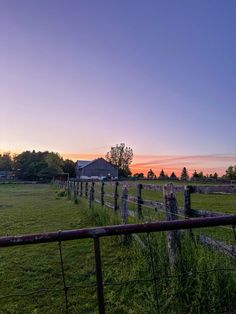 a fenced in field next to a house at sunset