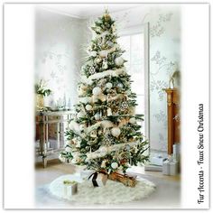 a decorated christmas tree in a living room with white and gold ornaments on the top