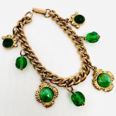 Vintage Peking Glass & Green Beaded Dangling Charm Bracelet. Etched gold plated metal chain with dangling gold tone Peking glass medallion and green glass beaded charms. In excellent vintage condition with minimal age appropriate wear. No chips no cracks. Measures 1 1/4 inches wide at widest point and is 7 1/4 inches long. Fold over clasp secure Gold-tone Metal Jewelry With Round Beads, Gold Jewelry With Dangling Round Beads Charms, Gold Jewelry With Dangling Round Beads, Green Metal Chain Jewelry, Vintage Green Jewelry With Chain, Green Vintage Charm Brass Jewelry, Green Brass Jewelry With Vintage Charm, Bohemian Gold Charm Bracelet In Brass, Bohemian Gold Brass Charm Bracelet