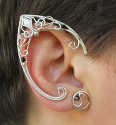 a person with some kind of ear piercing on their left side of the ear that is made out of silver wire