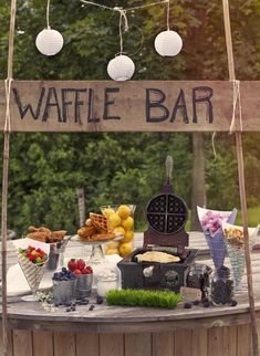 a waffle bar is set up outside on a table with fruit and other foods