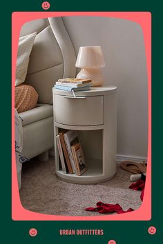 there is a small table with books on it and a lamp next to the bed