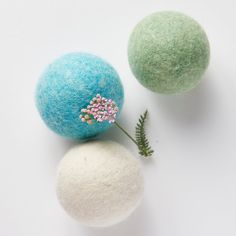 two balls with flowers on them sitting next to each other, one blue and the other green