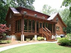 a large wooden house with lots of windows on it's front porch and stairs leading up to the second floor