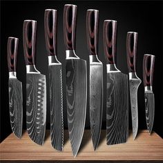 six knives are lined up in a row on a wooden table with black background and wood grained edges