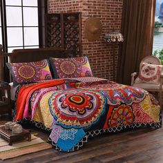 a bed room with a neatly made bed next to a brick wall and wooden floors