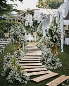 an outdoor wedding ceremony with white flowers and greenery on the aisle, surrounded by wooden pallets