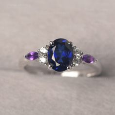 * The delicate ring displays sapphire as main stone. The cluster side stones make the ring similar to the blooming flower . For who wearing this special & delicate ring, will shine like a goddess. ◆ Production Description: Main stone Type: Lab Sapphire Main Stone Shape: Oval Cut Main Stone Size: 6*8mm (1.75ct) Side stone: CZ & Amethyst Metal: 925 Sterling silver - Other options available in the drop down menu ◆ Customization: √Free for Add Engraving √Other Metal Type Available √Other Gem Amethyst And Sapphire Ring, Sapphire Multi-stone Oval Diamond Ring, Oval Multi-stone Sapphire Cluster Ring, Elegant Multi-stone Sapphire Birthstone Ring, Elegant Sapphire Multi-stone Birthstone Ring, Elegant Sapphire Birthstone Ring With Multi-stone, Oval Multi-stone Sapphire Diamond Ring, Oval Sapphire Multi-stone Diamond Ring, Dainty Sapphire Ring For Promise