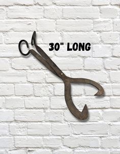 an old pair of scissors with the words 30'long on it against a white brick wall