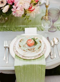 a table set with plates, silverware and flowers