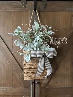 a basket hanging from the side of a wooden door with a ribbon tied around it