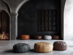 four leather stools sitting in front of an open fire place, with one foot on the floor