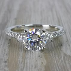 a three stone engagement ring with diamonds on the band and an oval cut diamond in the center