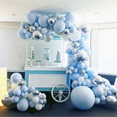 balloon arch with silver and white balloons on it in front of a mirror, blue walls and floor