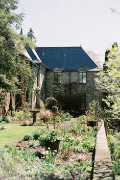 the house is surrounded by beautiful flowers and greenery, with a wooden walkway leading up to it