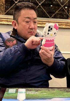 a man holding up a hello kitty cell phone