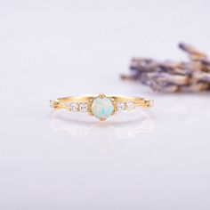 an opal and diamond ring sits next to lavender flowers