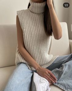 a woman sitting on top of a couch wearing a white sweater and blue jean pants