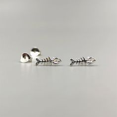 Exquisite fish bone stud earrings, meticulously handcrafted from high-quality sterling silver. These delicate earrings feature a charming fish bone design, measuring approximately 10mm in length and 4mm in width. With their lightweight construction, they offer both comfort and style. The fish bone symbolizes adaptability, resilience, and the ability to navigate through life's challenges with grace. Our fish bone stud earrings capture this essence, showcasing your inner strength and determination Fishbone Earrings, Earring Stacks, Fish Skeleton, Beautiful Baubles, Skeleton Earrings, Bone Earrings, Silver Fish, Fish Bone, Delicate Earrings