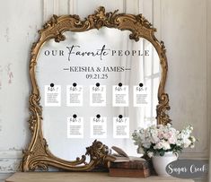 an ornate gold framed mirror with seating cards on it and a vase filled with flowers