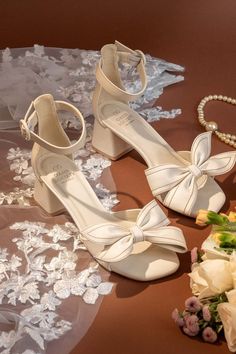 Vigo White Strappy Heel with Bow Front from Oasis Society, featuring a chic bow front and comfortable low heel, perfect for a bridal look. Summer Bow Heels With Round Toe, Summer Wedding Sandals With Bow Straps, Summer Block Heels With Bow Straps, Beige Heels With Bow For Summer, Beige Bow Heels For Summer, Summer Beige Heels With Bow, Spring Ankle Strap Sandals With Bow Straps, Spring Beige Heels With Bow, Beige Round Toe Sandals With Bow