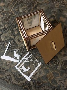 a cardboard box sitting on top of a carpet next to cut out deer and trees