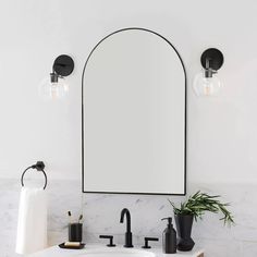 a bathroom with marble counter tops and black faucets, an oval mirror above the sink