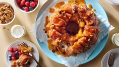 a bundt cake with fruit and nuts on it sitting on a table next to other desserts