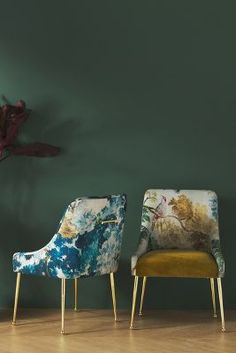 three chairs in front of a green wall with flowers on the back and gold legs