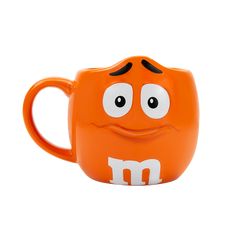 an orange mug with m on it's face and eyes, sitting in front of a white background