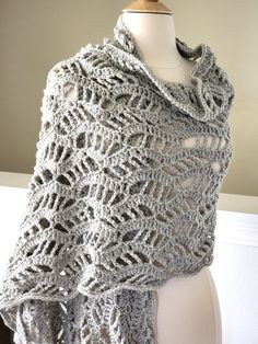 a white mannequin with a gray crochet shawl draped over it