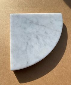 a close up of a white marble object on a brown surface with a shadow coming from it