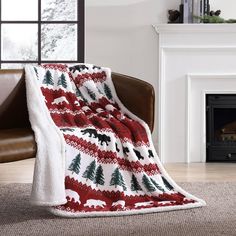 a red and white blanket sitting on top of a chair next to a fire place