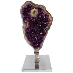 a piece of purple rock sitting on top of a metal stand in front of a white background