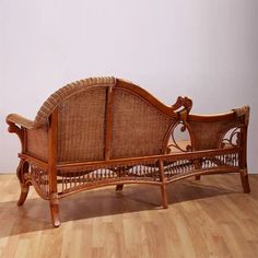 a wicker couch sitting on top of a hard wood floor next to a wall