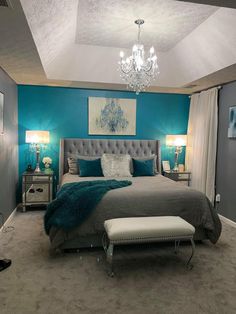 a bed room with a neatly made bed and a chandelier hanging from the ceiling