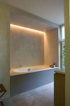 an empty bathroom with a large bathtub next to a table and chair in front of the window