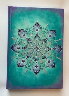 a blue and green painting with an intricate design on the front cover is hanging on a wall